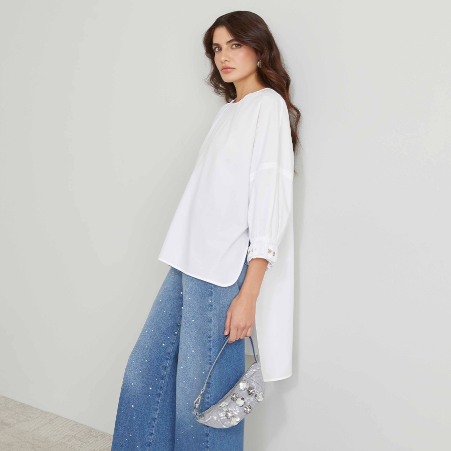 Modella indossa maxi camicia di colore bianco abbinata a jeans con strass.